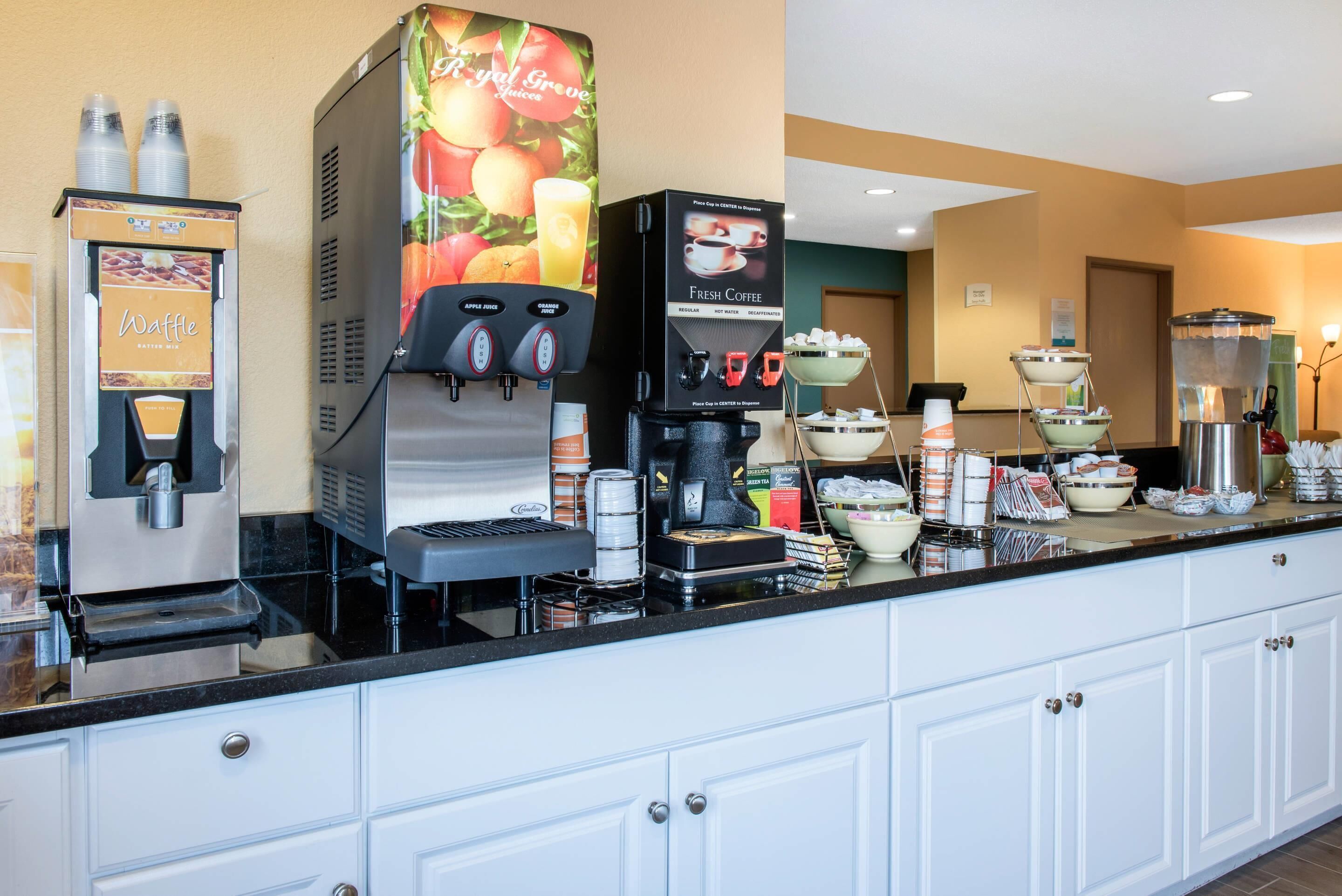 A self-service beverage station with options for apple juice, orange juice, and fresh coffee.