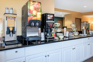 Una estación autoservicio para bebidas, con opciones de jugo de manzana, jugo de naranja y café recién hecho.