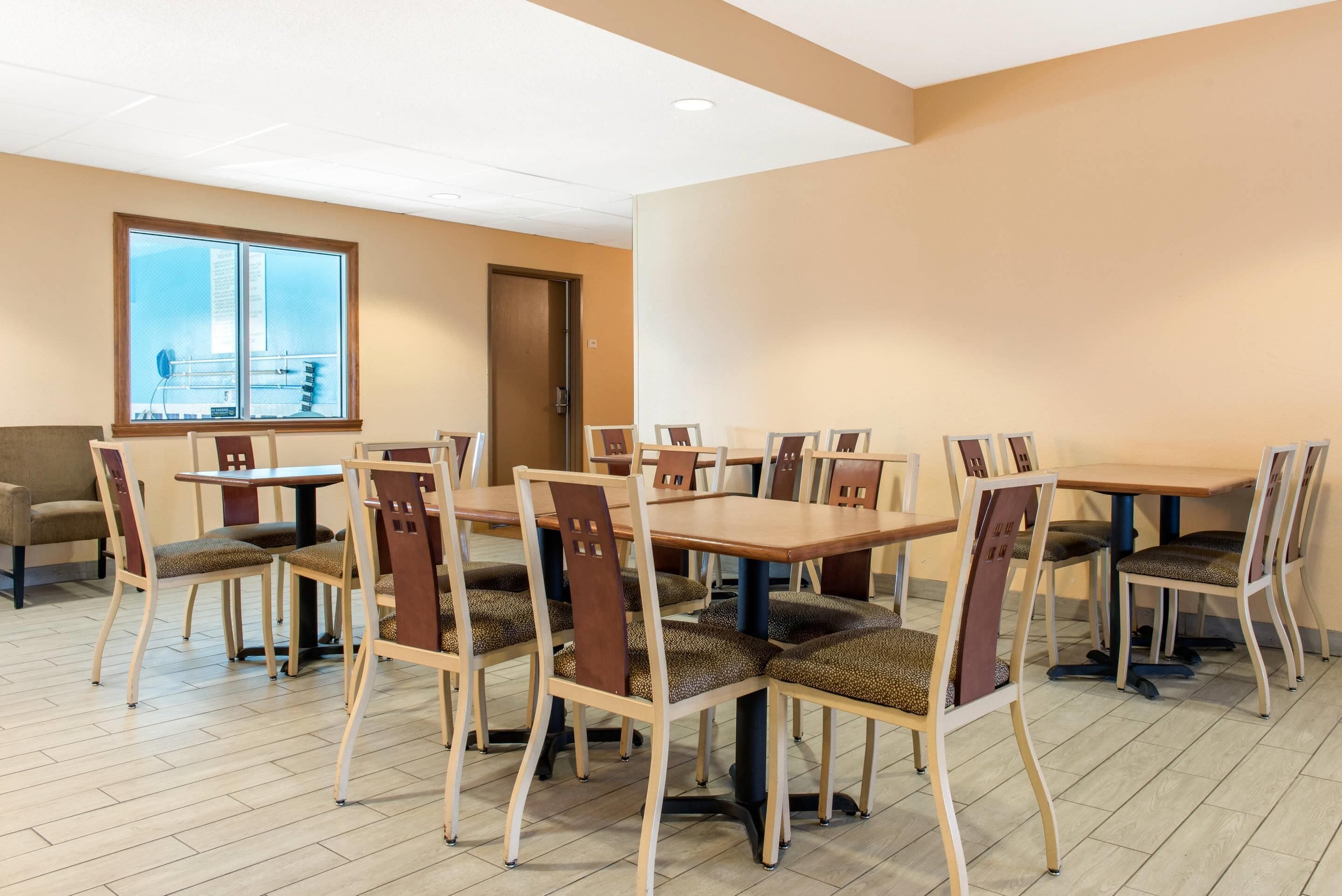 Un espace repas comprenant plusieurs tables et chaises, une grande fenêtre offrant une belle vue et une porte donnant sur une autre pièce.