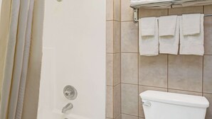 Un baño con bañera, inodoro y un perchero con varias toallas.