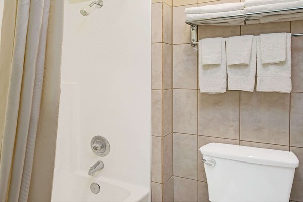 Un baño con bañera, inodoro y un perchero con varias toallas.