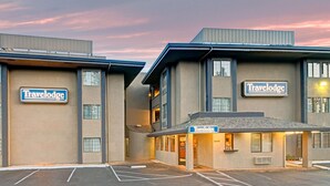 Un hotel Travelodge con una estructura de dos pisos, una entrada cubierta y un estacionamiento.