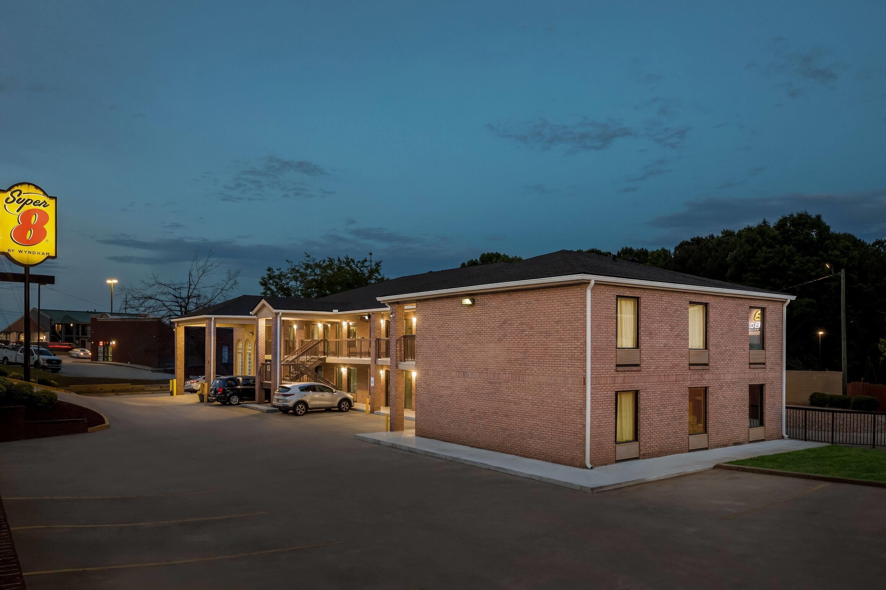 Un motel con fachada de ladrillo, una zona de estacionamiento techada y un letrero que dice 'Super 8 by Wyndham'.