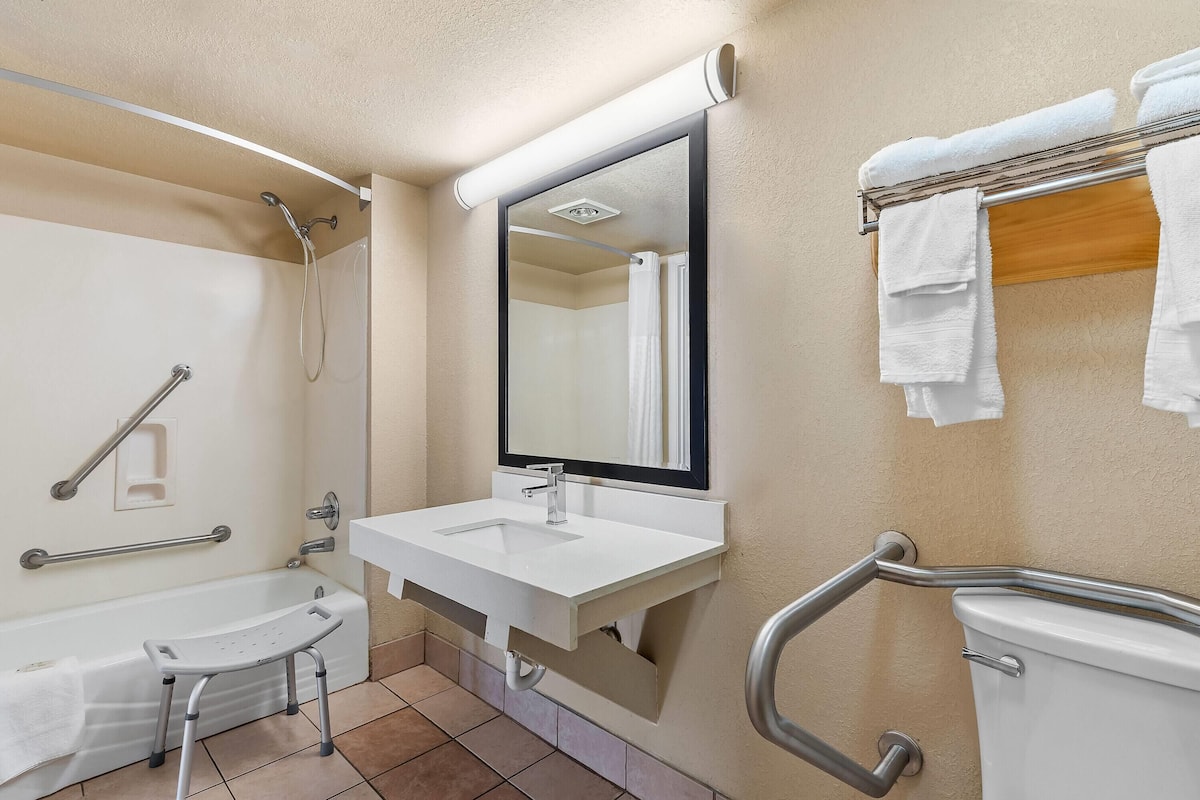 Un baño con bañera, lavamanos, espejo y un perchero para toallas.
