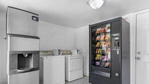 Una cocina compacta equipada con refrigerador, lavadora, secadora y máquina expendedora.