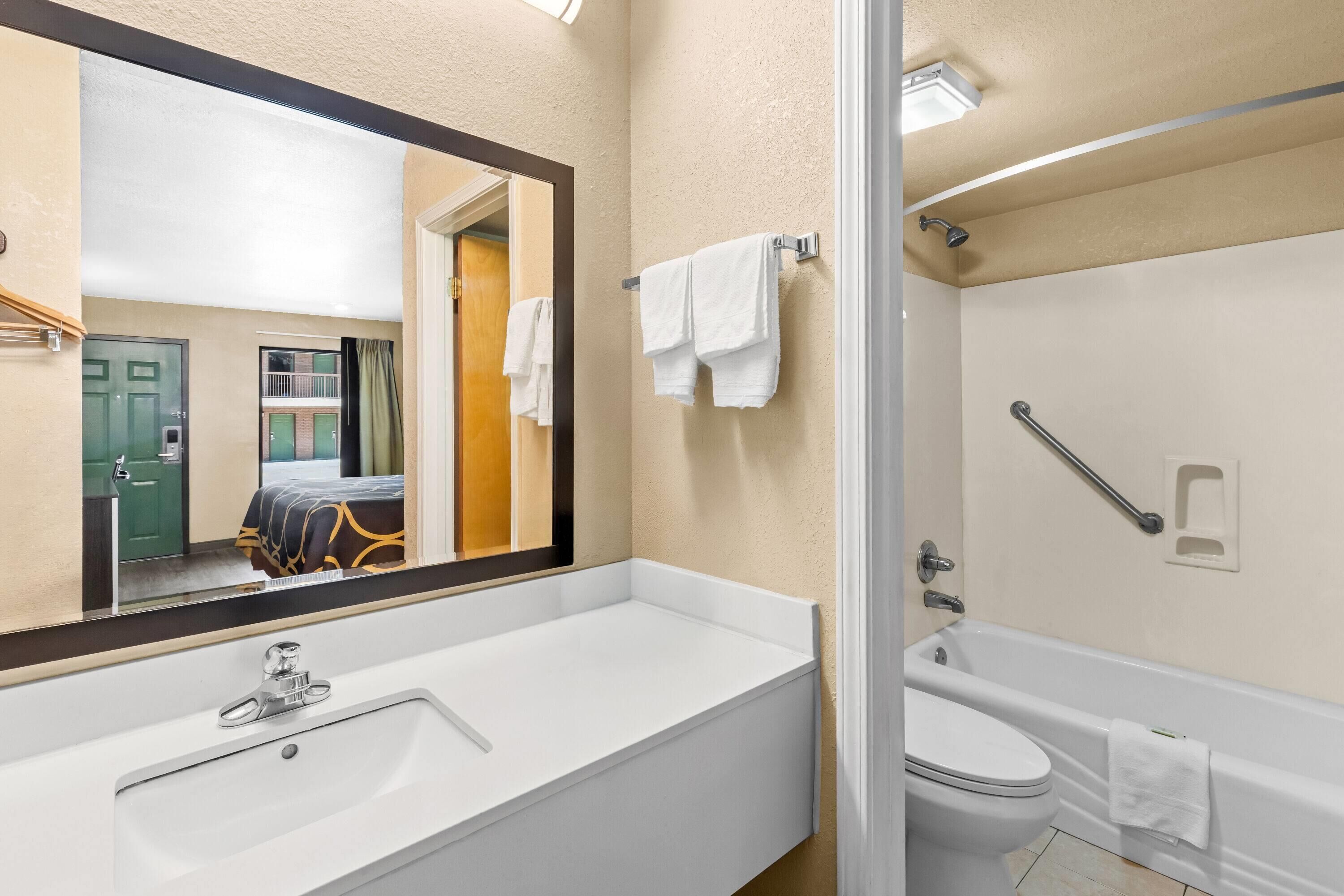 Ein Badezimmer mit großem Spiegel, Waschbecken, Toilette und Badewanne.