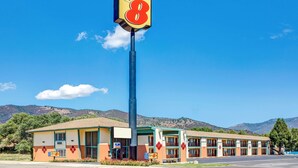 Un motel con un llamativo letrero de 'Super 8', un edificio de dos pisos con techo plano y un estacionamiento al frente.