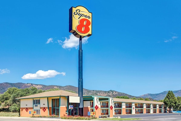 A motel with a prominent 'Super 8' sign, a two-story building with a flat roof, and a parking lot in front.