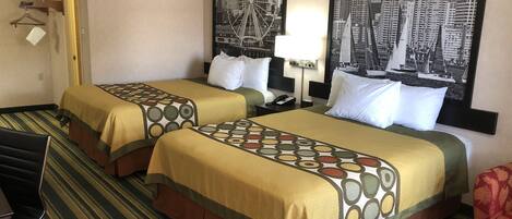 Habitación de hotel con dos camas, alfombra a rayas, un cuadro con vista a la ciudad, una lámpara y un perchero.