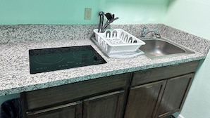 Una cocina con encimera de granito, estufa integrada, lavamanos y armarios de madera.