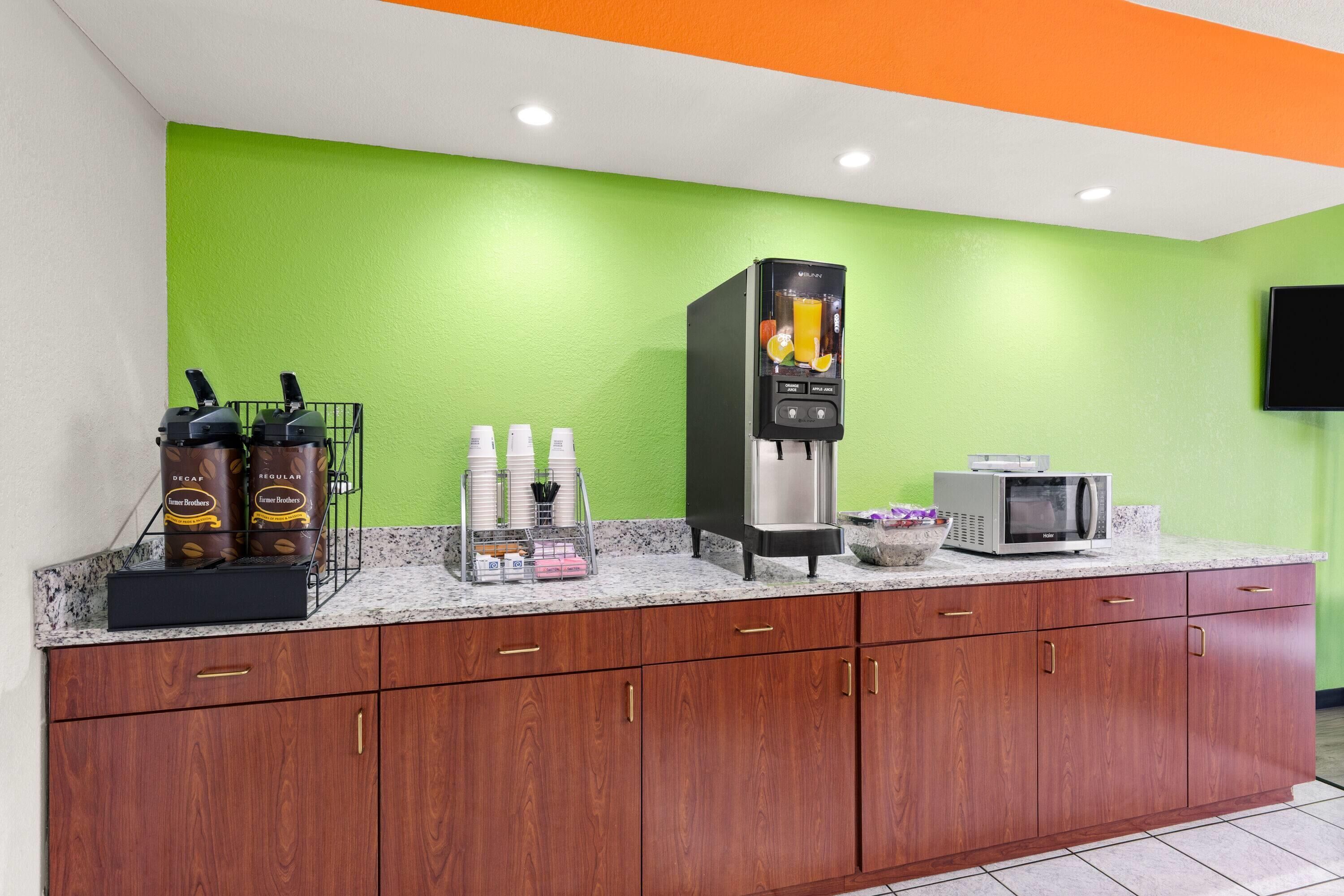 Un angolo cottura con macchina del caffè, forno a microonde e distributore di caffè.