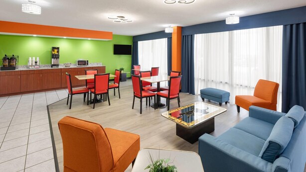 A modern hotel lobby with a green accent wall, a bar area, red and blue seating, and large windows with curtains. - Super 8 by Wyndham Bulls Gap Greeneville Area (Bulls Gap)