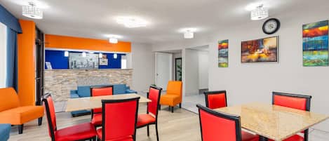 A modern dining area with red and orange chairs, a wooden table, and a blue sofa.