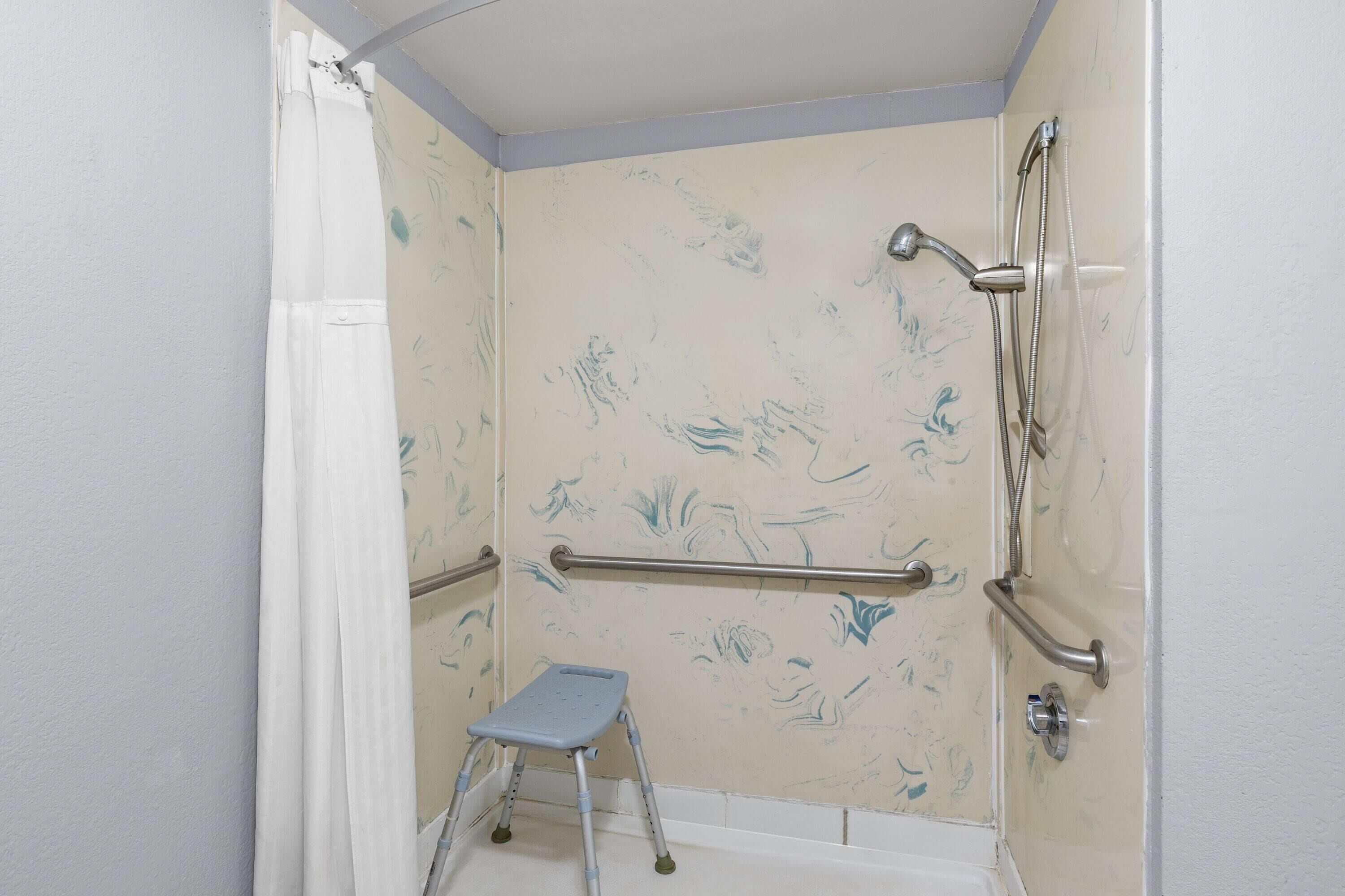 Een badkamer met een douche, grepen en een opstapje.