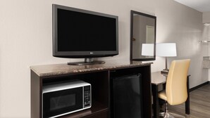 A hotel room with a flat-screen TV, a microwave, a refrigerator, a chair, and a lamp. - Super 8 by Wyndham Bulls Gap Greeneville Area (Bulls Gap)