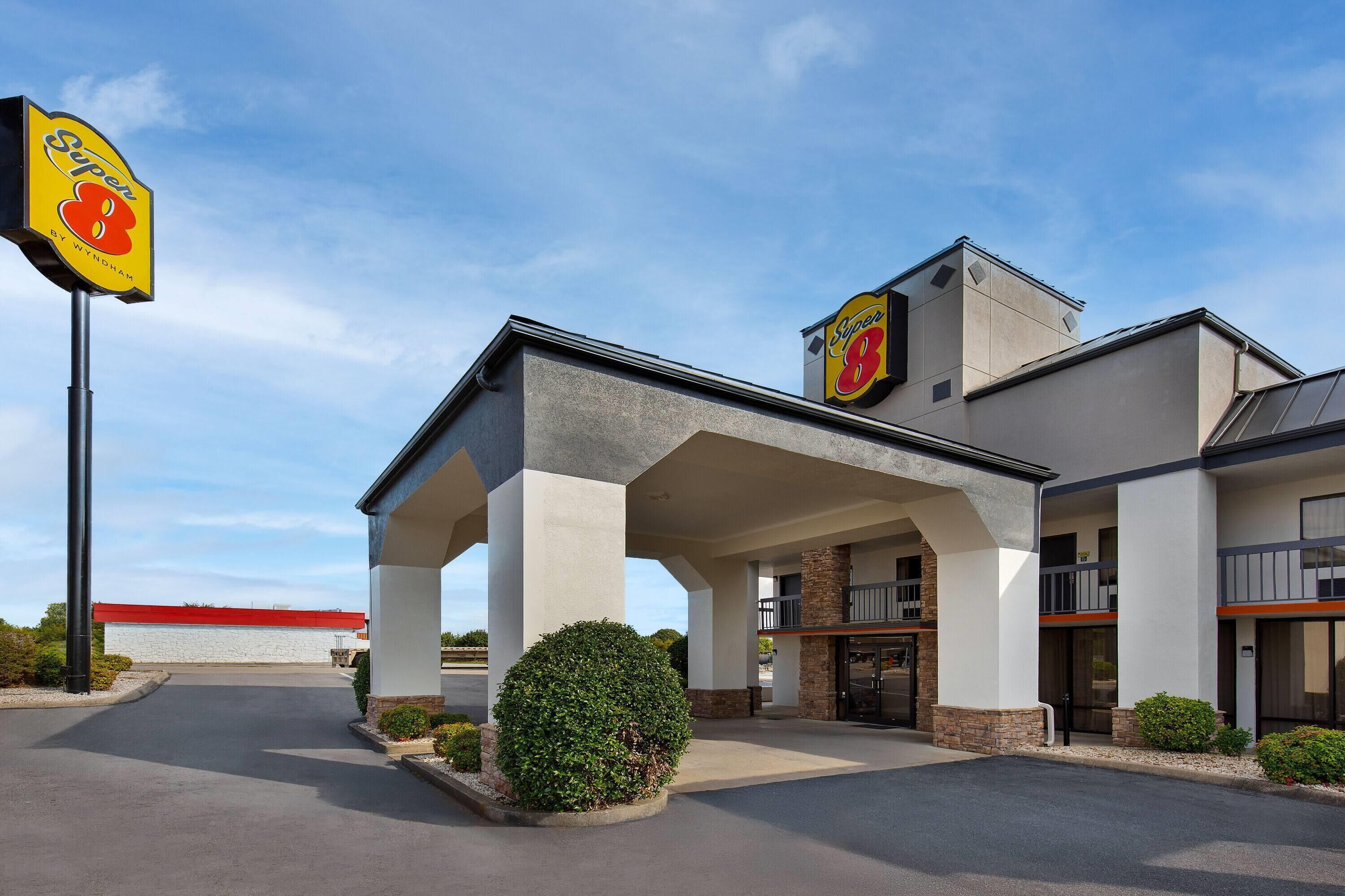 Un hotel con ingresso coperto, un evidente cartello 'Super 8' e un tetto rosso.