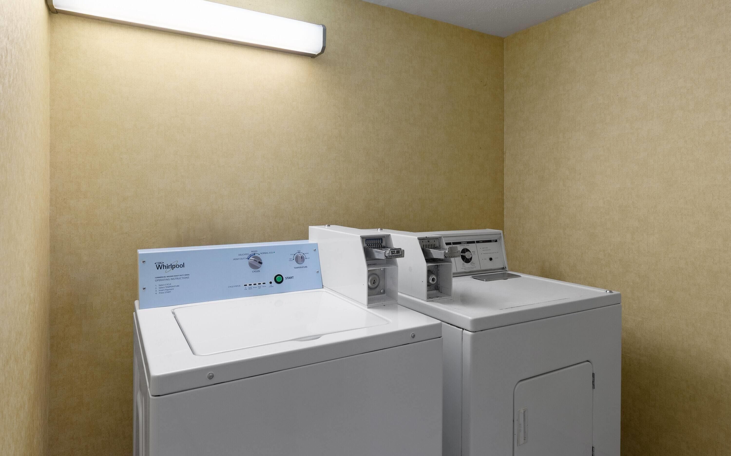 A Whirlpool washer and dryer in a laundry room with beige walls and a white ceiling.