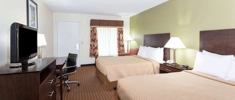 A hotel room with two beds, a desk with a TV, a chair, and a lamp.