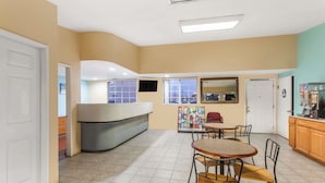Una habitación con cocina, una mesa de comedor con sillas, un refrigerador y un televisor pequeño.