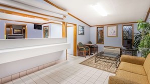 A spacious living area with a high ceiling, a dining table with chairs, a sofa, and a large plant. - Knights Inn Columbia (Columbia)
