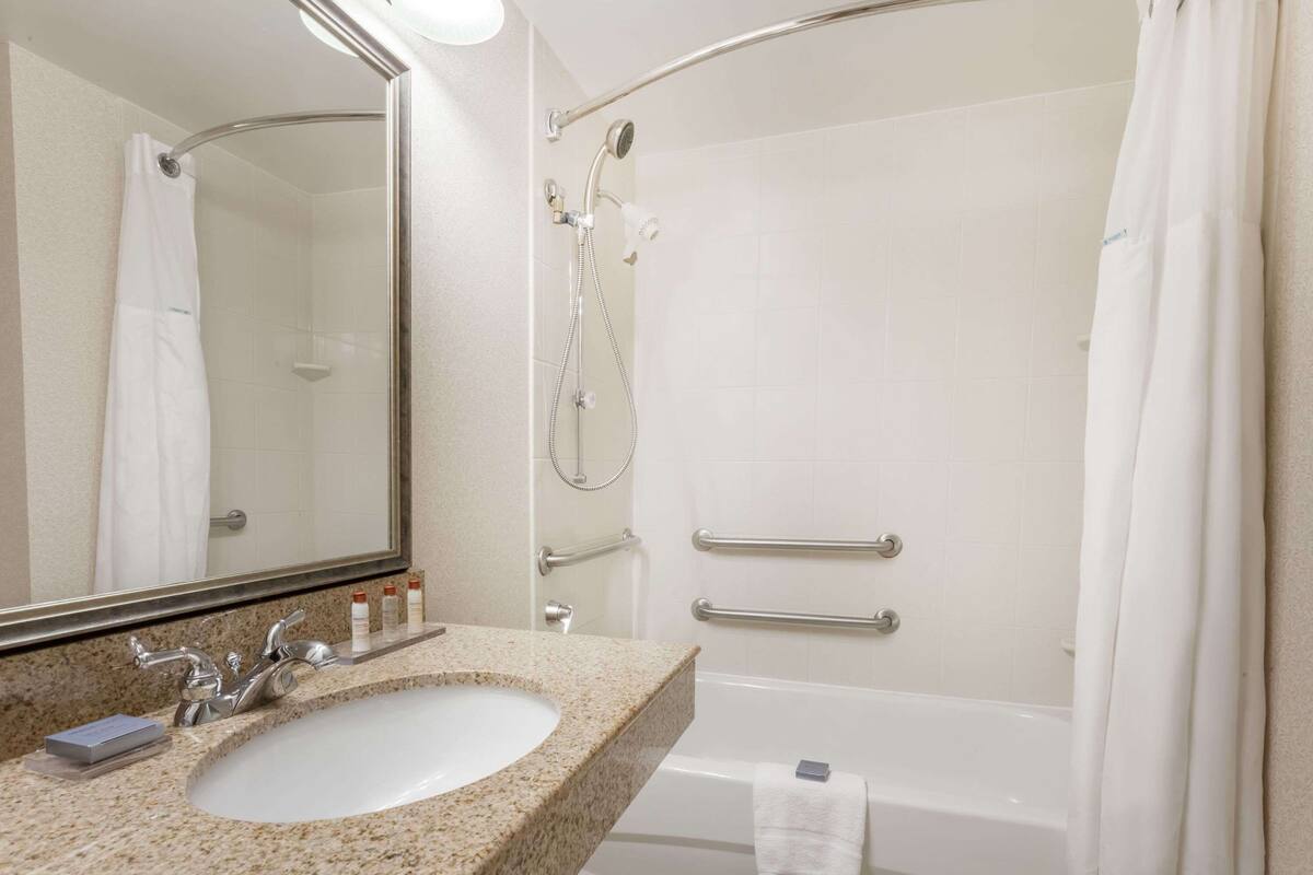 Une salle de bain équipée d’un lavabo, d’un miroir, d’une douche et d’une baignoire.