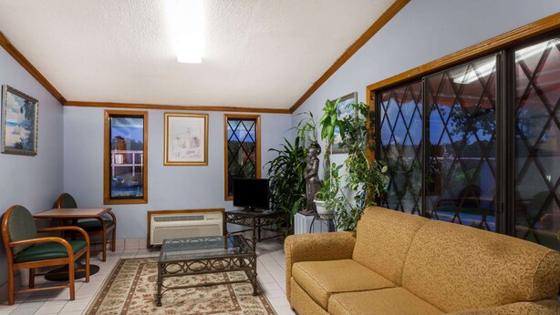 A living room with a sofa, chairs, a coffee table, a TV, and a radiator. - Knights Inn Columbia (Columbia)
