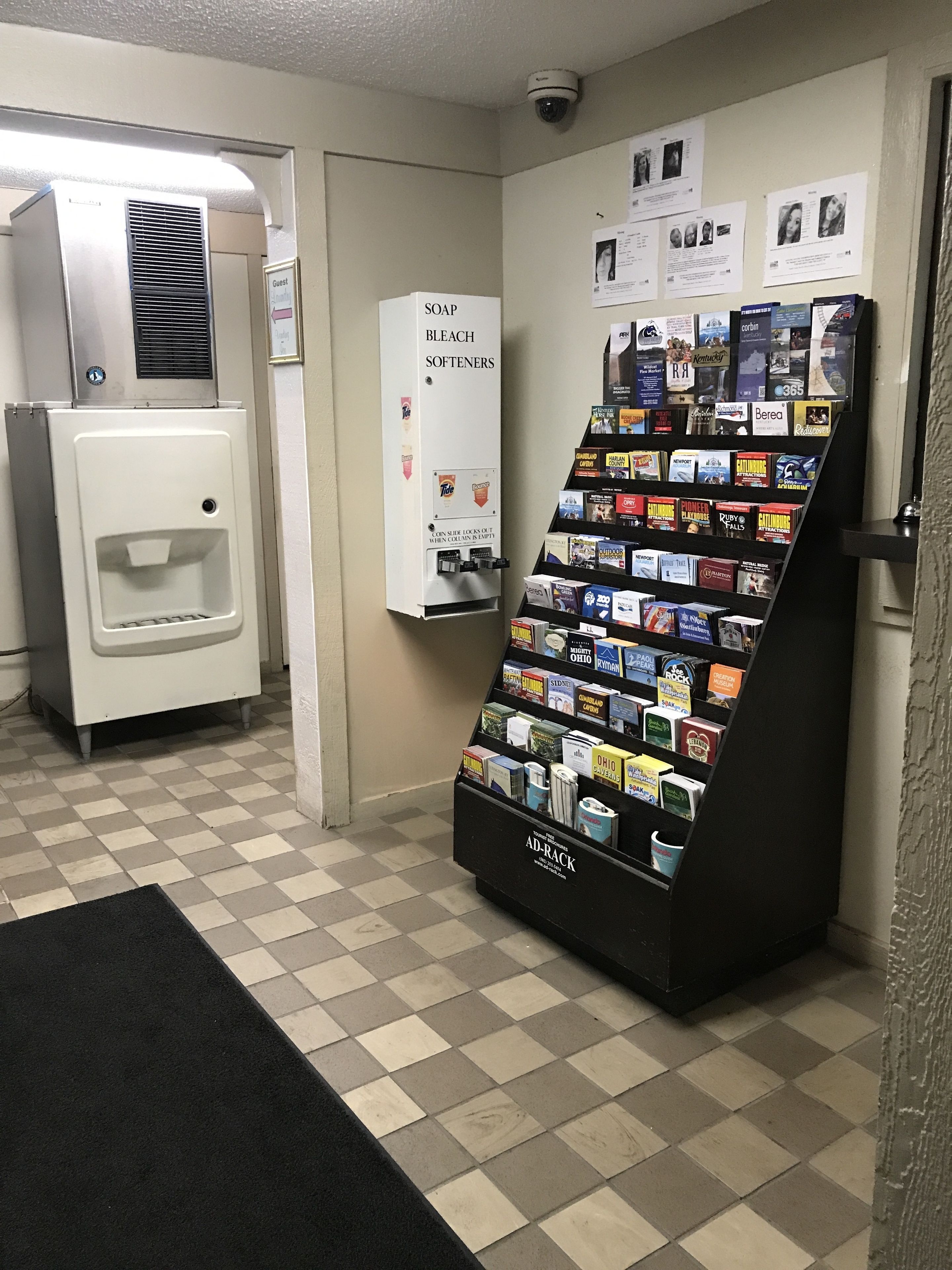 Rebost d'hotel amb una màquina de begudes automàtica, un dosificador de sabó i suavitzant, i un expositor AD-RACK de revistes i llibres.