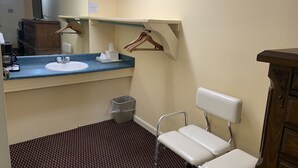 A bathroom with a sink, mirror, and a chair.