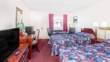 Habitación de hotel con dos camas, televisor, escritorio con lámpara y ventana con cortinas.