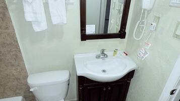 A bathroom with a white toilet, a sink with a mirror above it, and a hairdryer on the wall.