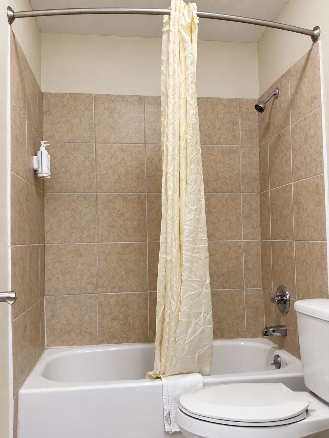 A bathroom with a bathtub, toilet, and a shower curtain.