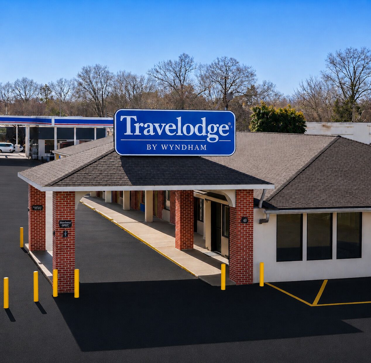 A Travelodge by Wyndham with a covered entrance, brick pillars, and a clear sky.