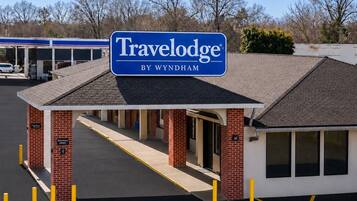 A Travelodge by Wyndham with a covered entrance, brick pillars, and a clear sky.