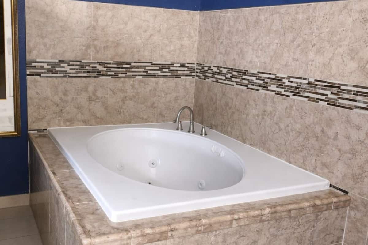 A bathroom with a large bathtub, beige marble tiles, and a blue accent wall.