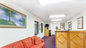 Ein Korridor mit einer roten Couch, einem Holzbüro und gerahmten Kunstwerken an den Wänden.