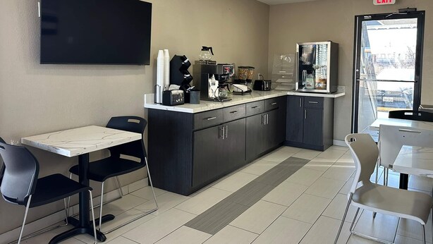 A modern kitchen area with a flat-screen TV, coffee machines, and a refrigerator. - Super 8 by Wyndham Waco North I-35 (Waco)