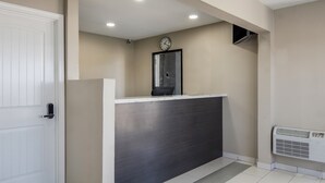 A reception area with a white door, a reception desk, a clock on the wall, and an air conditioning unit. - Super 8 by Wyndham Waco North I-35 (Waco)