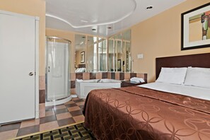 A hotel room with a bed, a shower, a bathroom mirror, and a door. - Knights Inn Trevose (Feasterville-Trevose)