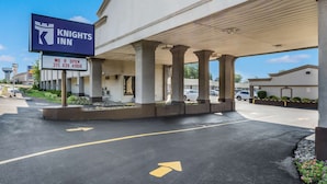 Entrada de un hotel Knights Inn con un cartel, un estacionamiento y cielo despejado.