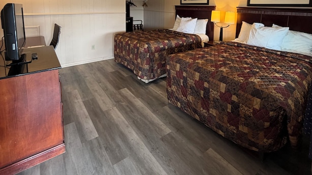 Habitación de hotel con dos camas, un escritorio, un televisor y una lámpara.