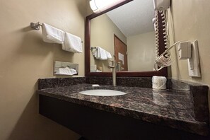 A bathroom with a granite countertop, a sink, a mirror, and a towel rack. - Super 8 by Wyndham Normal Bloomington (Normal)