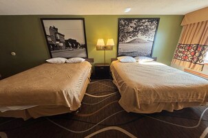 Habitación de hotel con dos camas, una mesita de noche con lámparas, un cuadro en la pared y una alfombra estampada.