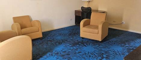 Une pièce comprenant deux fauteuils, une petite table avec une lampe et un tapis à motifs.