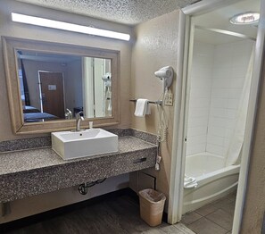 Une salle de bain équipée d’un lavabo, d’un miroir, d’un sèche-cheveux et d’une douche.