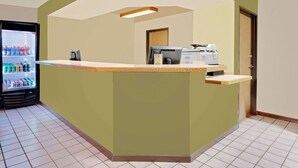 A reception area with a counter, a refrigerator stocked with beverages, and a door leading to another room.