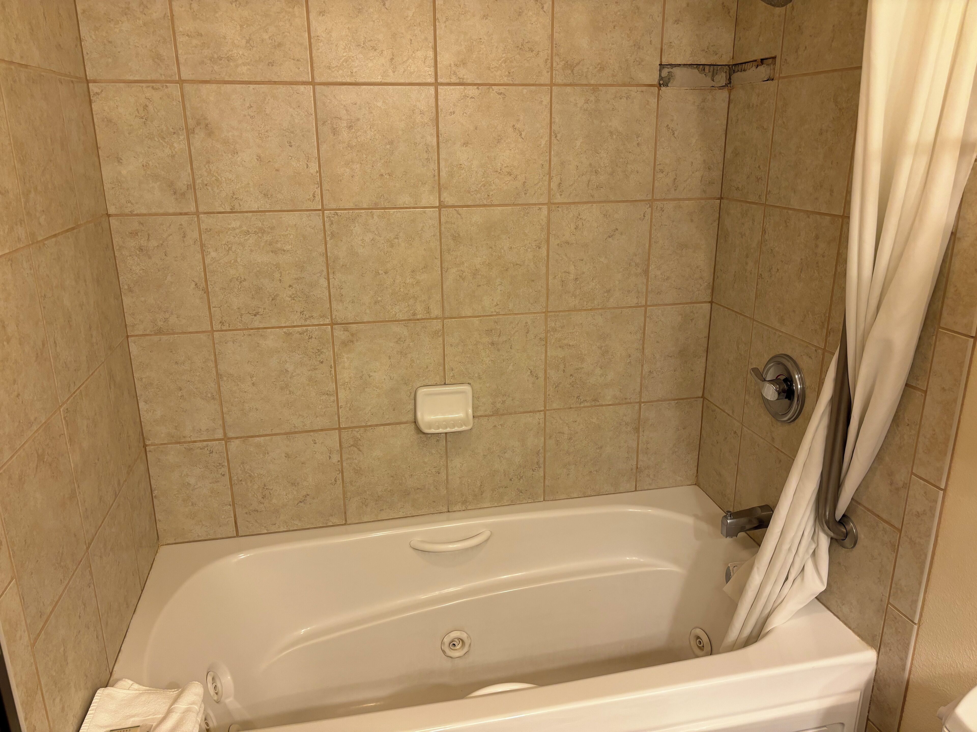 Une salle de bain avec une baignoire, un rideau de douche et un porte-savon.