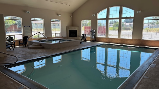 Una piscina interior con agua cristalina, rodeada de amplios ventanales y una zona de sauna.