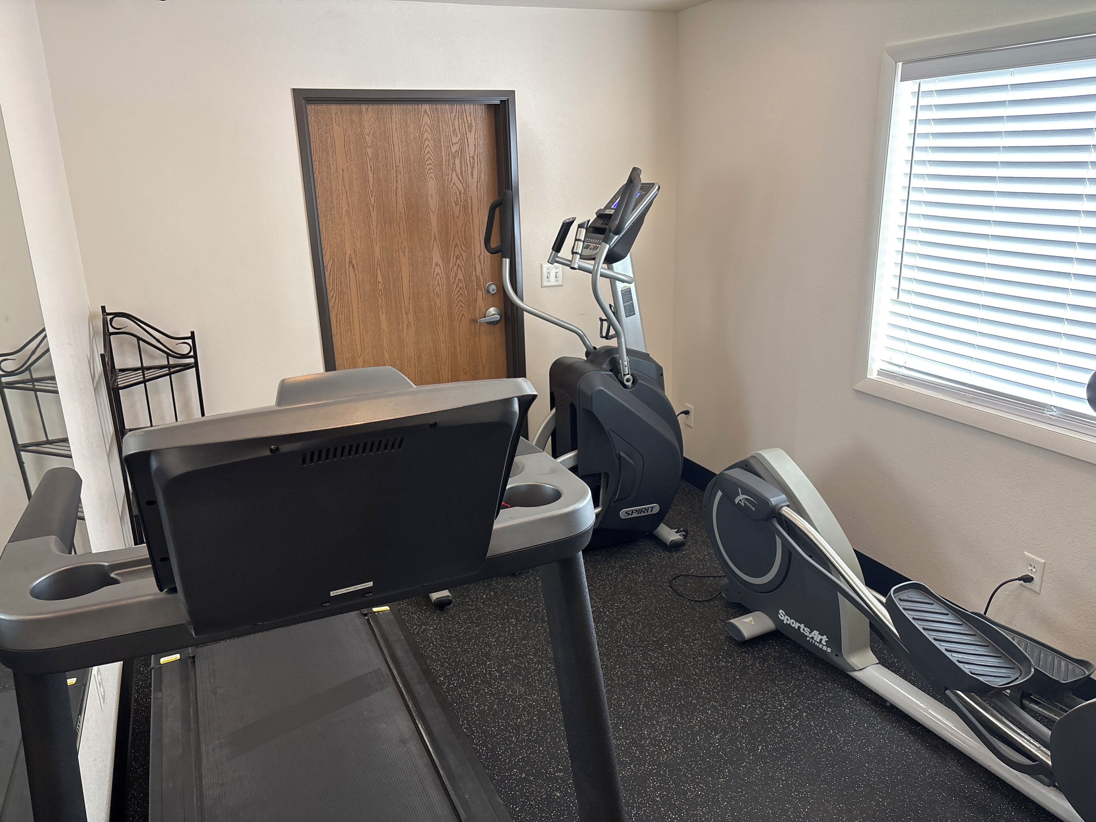 A gym with a treadmill, elliptical, and stationary bike.