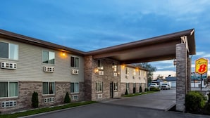 Un motel con fachada de ladrillo, múltiples ventanas y un corredor cubierto que lleva a la entrada.