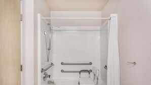 A bathroom with a bathtub, grab bars, a showerhead, and a towel rack. - Hotel Hamilton (Hamilton)